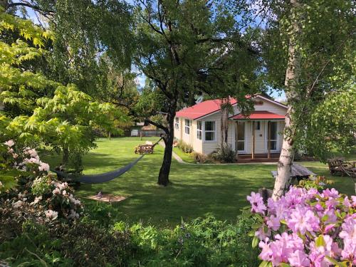 una casa con una hamaca en un patio con flores en Tailor Made Tekapo Accommodation - Guesthouse & Hostel, en Lake Tekapo