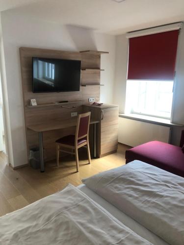 a bedroom with a desk with a television and a bed at Hotel & Gastropark Loemühle in Marl