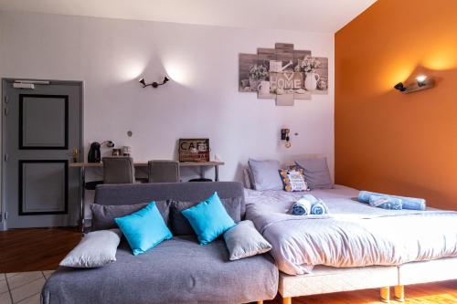 ein Schlafzimmer mit einem Bett und einem Sofa mit blauen Kissen in der Unterkunft Cosy'Appart - LE BOUQUET in Rouen