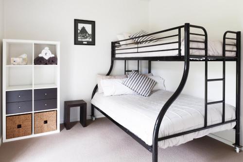 a bedroom with a black bunk bed with white sheets at Sandy point hideaway in Sandy Point