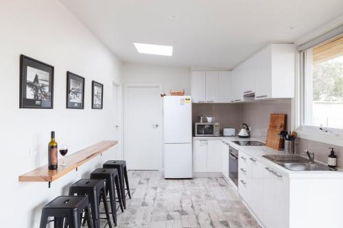 a white kitchen with black chairs and a white refrigerator at Sandy point hideaway in Sandy Point