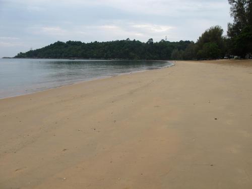 an empty beach with trees in the distance at MJ Boutique Hotel Khao Lak in Khao Lak