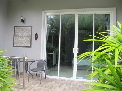 a patio with a table and chairs and sliding glass doors at MJ Boutique Hotel Khao Lak in Khao Lak