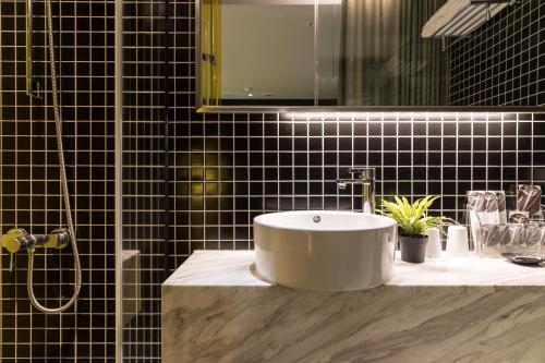 a bathroom with a white sink and black tiles at Vendome East Inn in Taipei