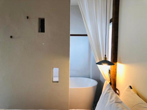 ein Bad mit einer Badewanne, einem Bett und einem Fenster in der Unterkunft Casa Ostia in Altstadt von Hengchun