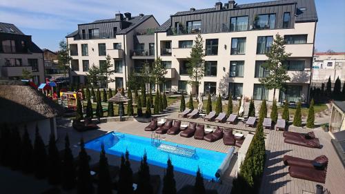 un hotel con piscina e sedie e un edificio di Mill house apartments a Palanga