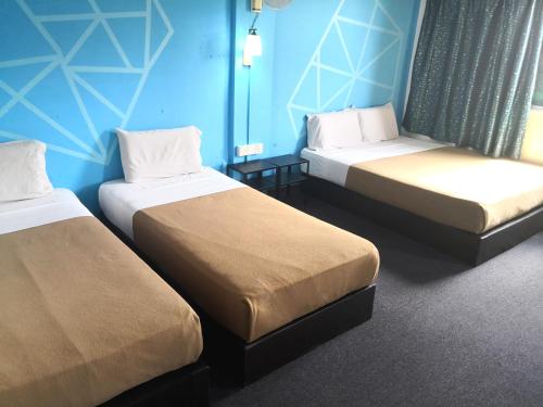 2 camas en una habitación con paredes azules en HOTEL SERI KOTA SATU, en Kota Tinggi