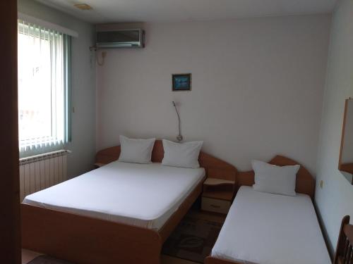 two beds in a small room with a window at Hotel Tsarevets in Asenovgrad