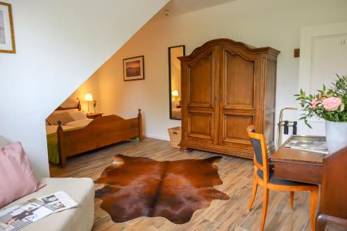 a living room with a desk and a bedroom with a bed at Hotel Gut Moschenhof in Düsseldorf