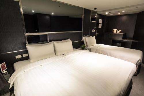 a bedroom with two beds with white pillows at Vendome East Inn in Taipei