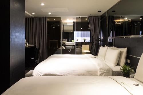 a hotel room with two beds and a bathroom at Vendome East Inn in Taipei