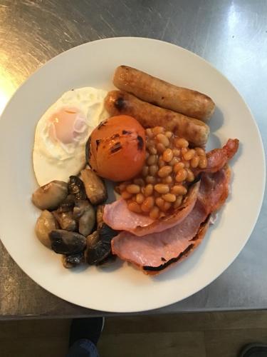 a plate of breakfast food with eggs bacon beans and sausage at The Hub at Abercrave in Abercraf