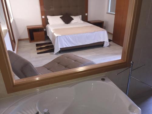 a bathroom with a tub and a bed with a mirror at Quinta de Real in Valença