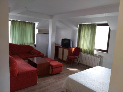 a living room with a red couch and a chair at ХОТЕЛ НИК in Asenovgrad