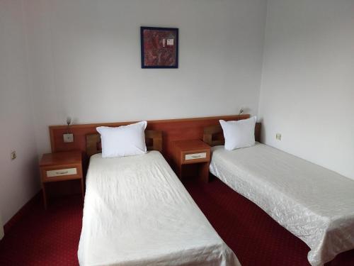two beds in a room with white sheets at ХОТЕЛ НИК in Asenovgrad