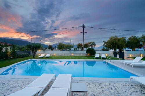 a swimming pool with chairs and a sunset at Alancia Suites in Sami
