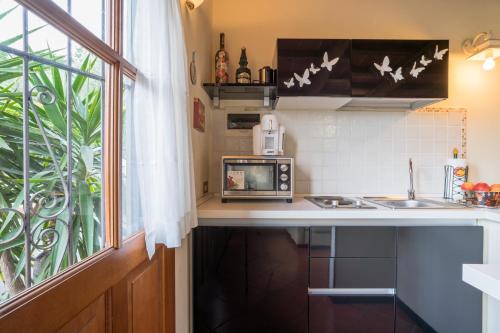 a kitchen with a microwave and a sink and a window at B&B Rosso Baccara in Montevettolini