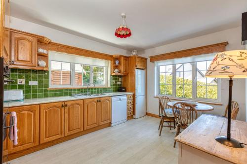 a kitchen with wooden cabinets and a table and chairs at Shearwater Self Catering in Union Hall