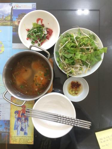 a table with four plates of food and a pot and salad at Lama Homestay in Hue