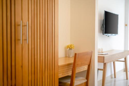 a room with a desk and a table with a television at Babylon Garden Da Nang in Da Nang