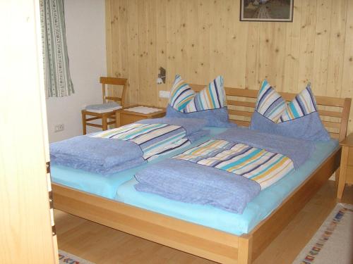 um quarto com uma cama com lençóis e almofadas azuis em Appartement Bischof em Schoppernau