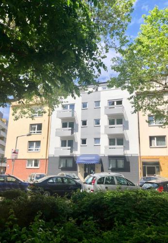 a white building with cars parked in a parking lot at City Hotel und City Apartments Centrum in Kaiserslautern