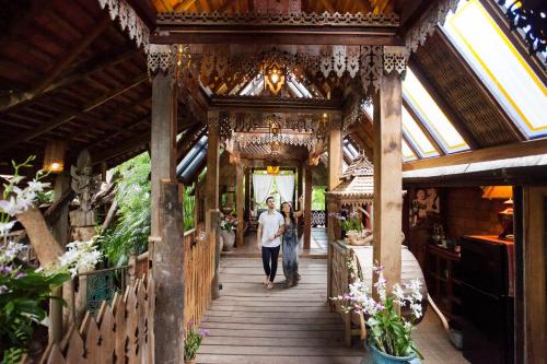 a woman walking down a wooden walkway in a flower shop at BaanBooLoo Village in Chiang Mai