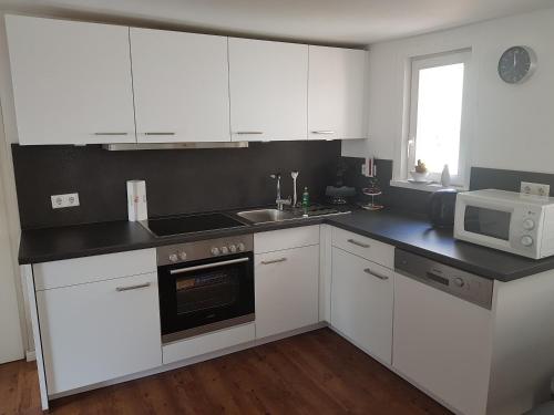 a kitchen with white cabinets and a sink and a microwave at Ferienhaus Nr. 10 in Buergstadt