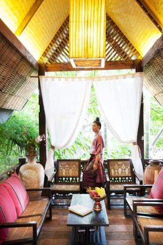 a woman standing in a room with chairs and tables at BaanBooLoo Village in Chiang Mai