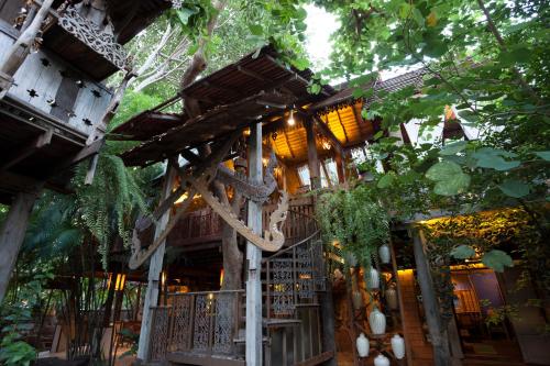 a wooden building with a tree branch hanging from it at BaanBooLoo Village in Chiang Mai