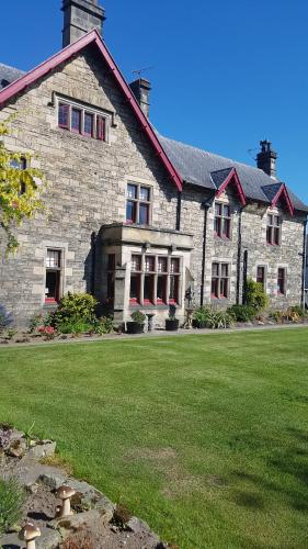 uma grande casa de pedra com um relvado verde em St Michaels Guest House em Elgin