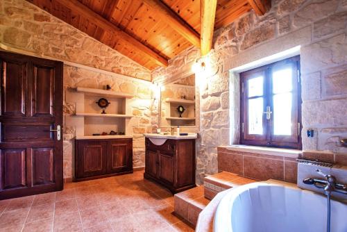 a large bathroom with a tub and a window at The Vivian - Luxury Stone Villa in Koiliomenos