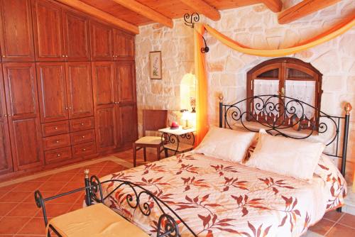 a bedroom with a bed in a room with wooden cabinets at The Vivian - Luxury Stone Villa in Koiliomenos