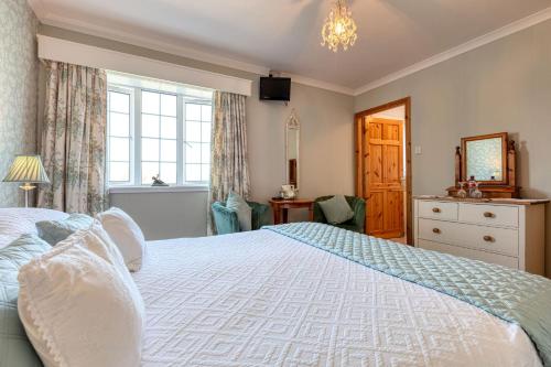 a bedroom with a bed and a dresser and a window at Shearwater Country House Accommodation in Union Hall