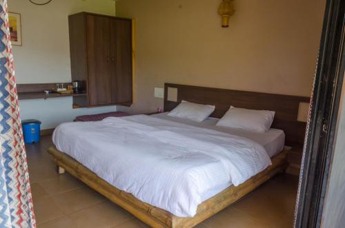 a bedroom with a large bed with white sheets and pillows at Avanti Kalagram Hill Top Resort, Mulshi in Kolvan