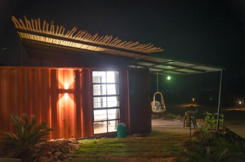 a lit up shed at night with a swing at Avanti Kalagram Hill Top Resort, Mulshi in Kolvan