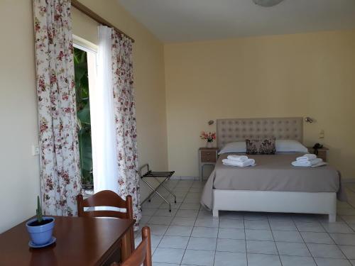 1 dormitorio con cama, mesa y ventana en Green Bay Hotel, en Karavomylos