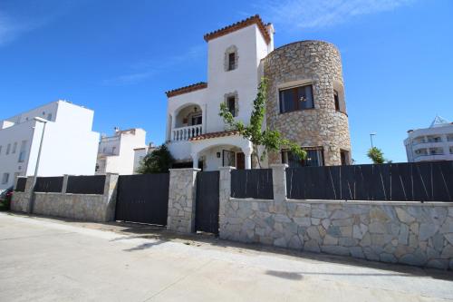 a house with a stone wall and a fence at Apart-rent Casa con piscina Sant Maurici 0191 in Empuriabrava