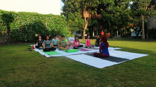 a group of people sitting in a yoga pose on the grass at Metland Hotel Cirebon in Cirebon