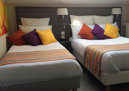 a hotel room with two beds with colorful pillows at Hôtel de L'Avenue in Tarbes