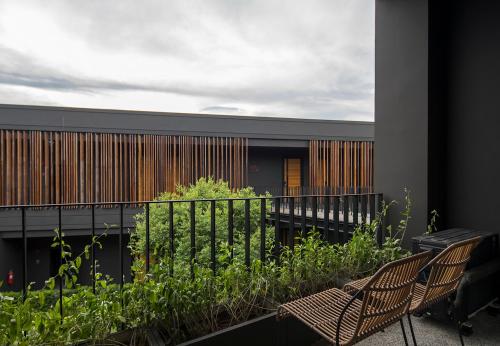 a balcony with two chairs and plants on a building at Wheeler Bed &Bike in Bangsaen