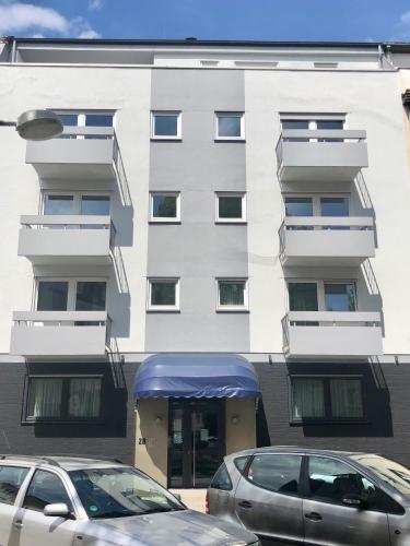 a white building with cars parked in front of it at City Hotel und City Apartments Centrum in Kaiserslautern