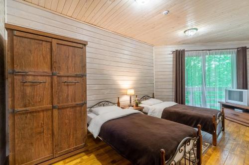 two beds in a room with wooden walls and a tv at Bird Valley in Sinyak