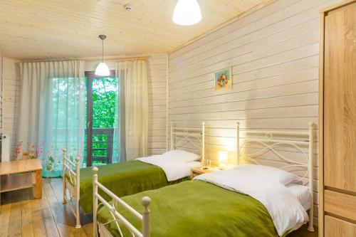 two beds in a room with wooden walls at Bird Valley in Sinyak