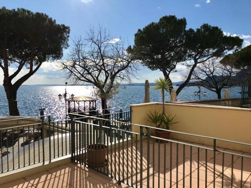 a view of the water with a fence and trees at Hotel Roma in Garda