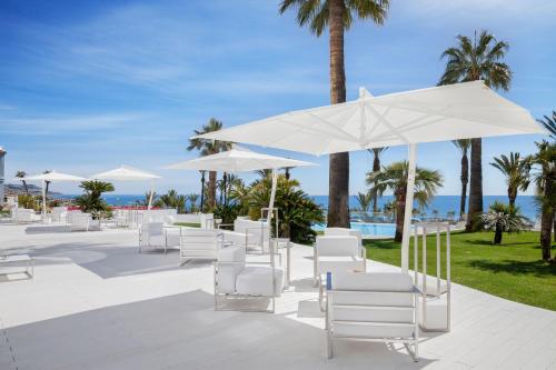 a row of white chairs and umbrellas at a resort at Miramare The Palace Resort in Sanremo
