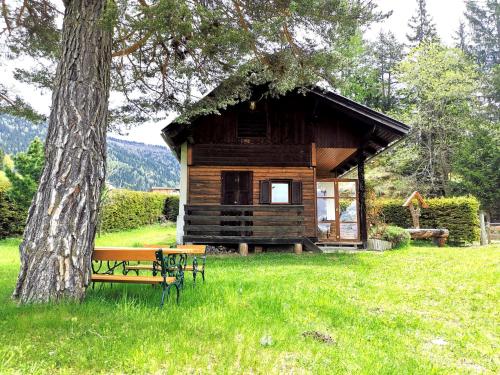 a log cabin with a bench next to a tree at Waldheimat in Fresach