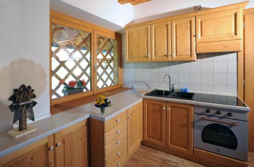 a kitchen with wooden cabinets and a sink and a window at Albergo Diffuso Ravascletto in Ravascletto