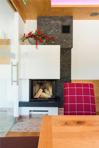 a living room with a fireplace and a red chair at Hotel Theresia in Ramsau im Zillertal