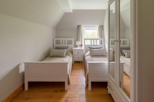 a small room with two beds and a mirror at Lehrerwohnung in Tümlauer Koog